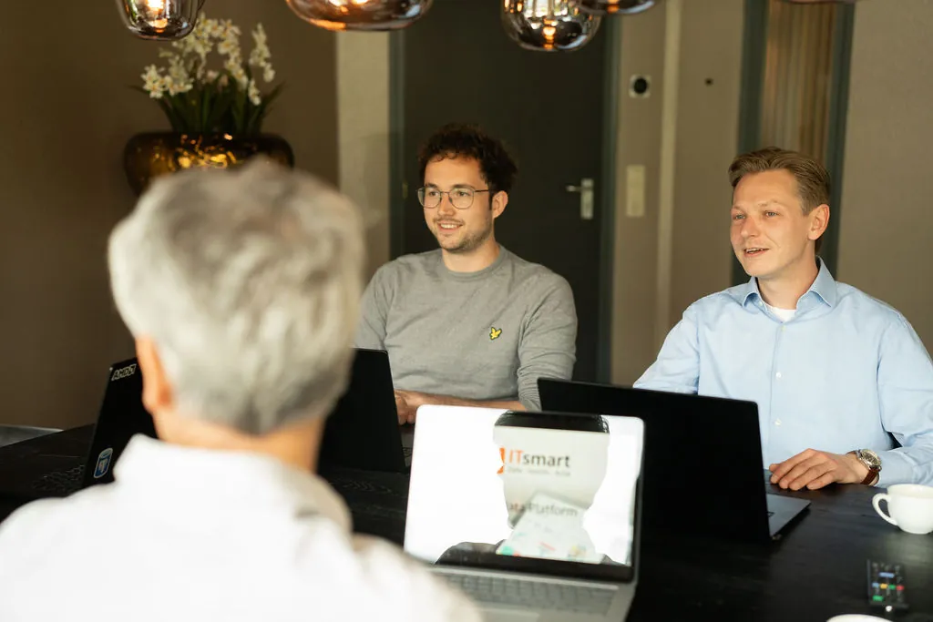 Twee collega's van ITsmart lachen bij een laptop met het Smart Data Platform in beeld